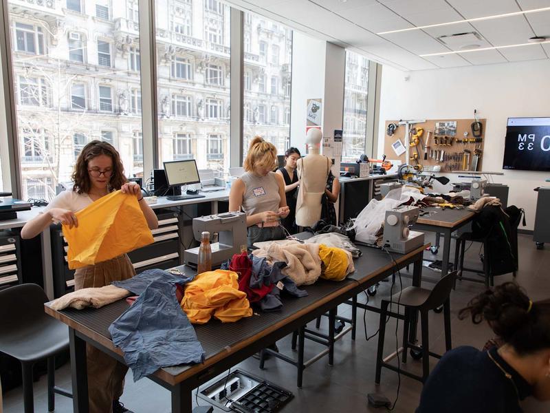 学生 work with fabric in a large room with sewing machines